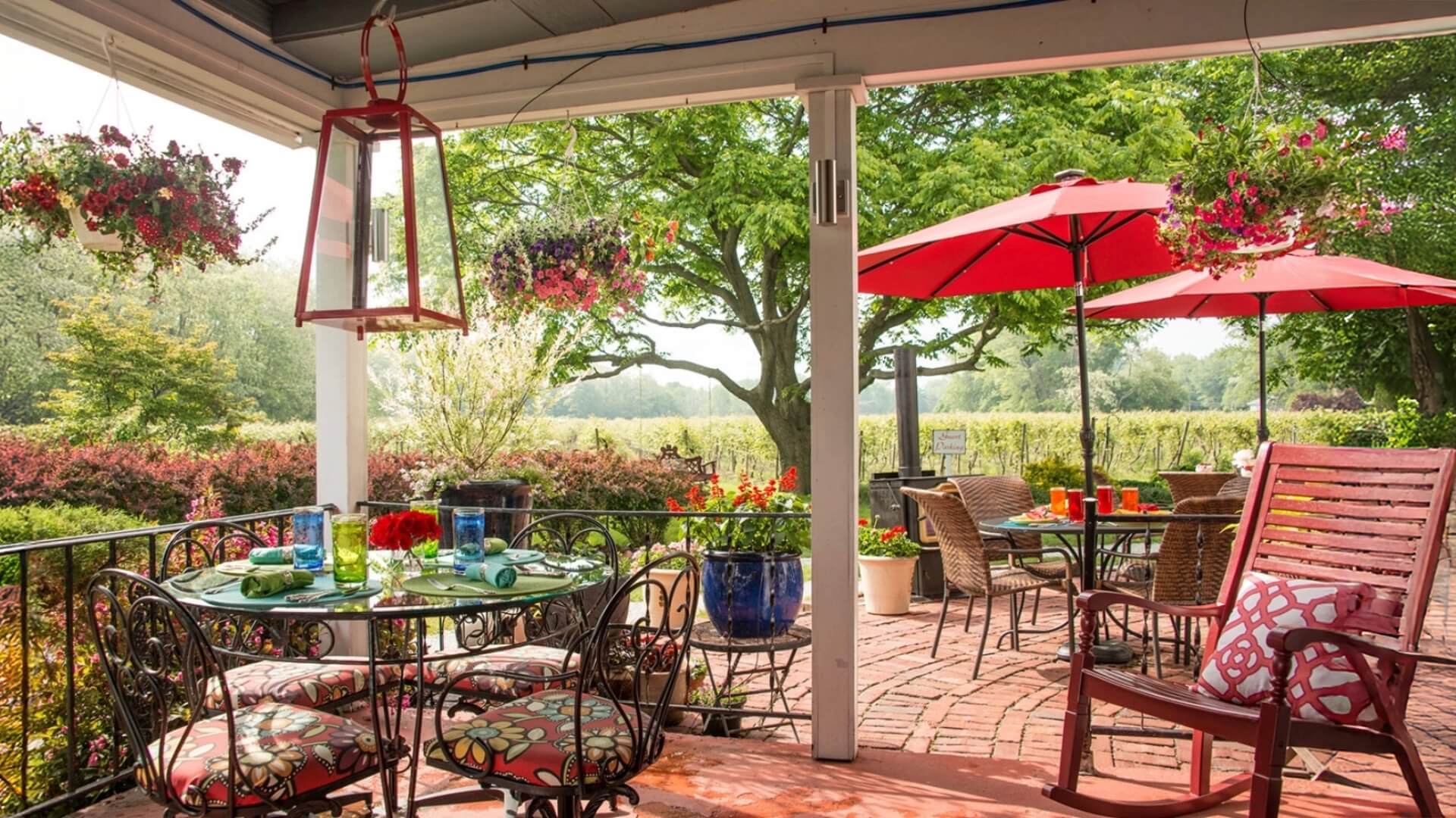 A cozy patio with a table set for dining, surrounded by greenery and colorful flower arrangements.